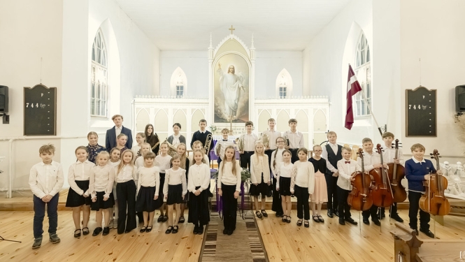 Audzēkņi pēc koncerta altāra priekšā nostājušies ar instrumentiem rokās